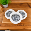 Three DryFlush refill cartridges with white bagasse rims and silver Mylar liners on a wooden tabletop